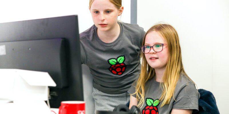 Two girls code together at a computer.