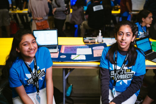 Two teenage girls participating in Coolest Projects shows off their tech project.