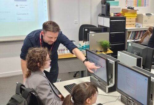 An educator points to an image on a student's computer screen.