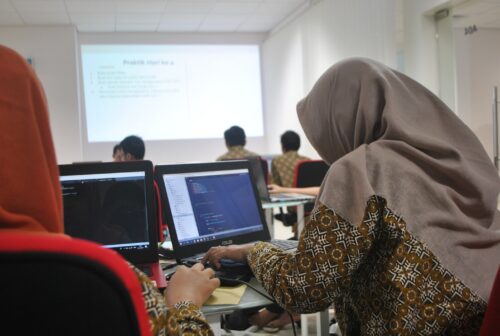 A young woman codes in a computing classroom.
