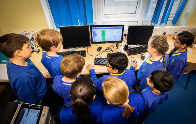 Jay teaches a group of schoolchildren how to use the programming language Scratch on a computer.