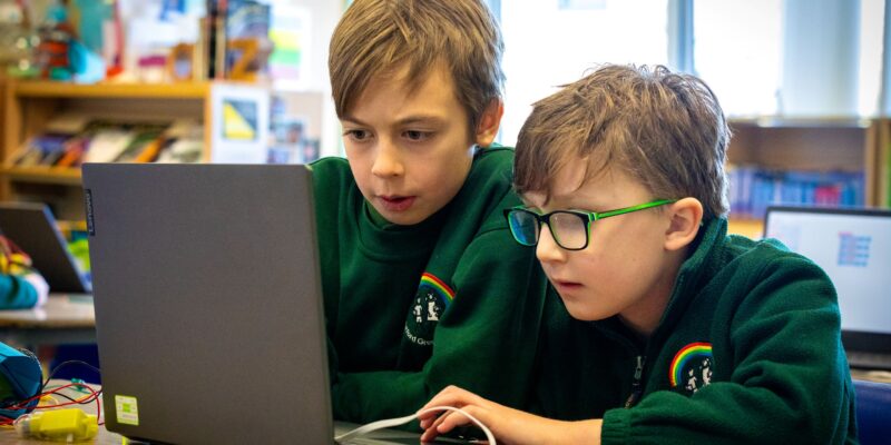 Two learners sharing a laptop in a coding session.