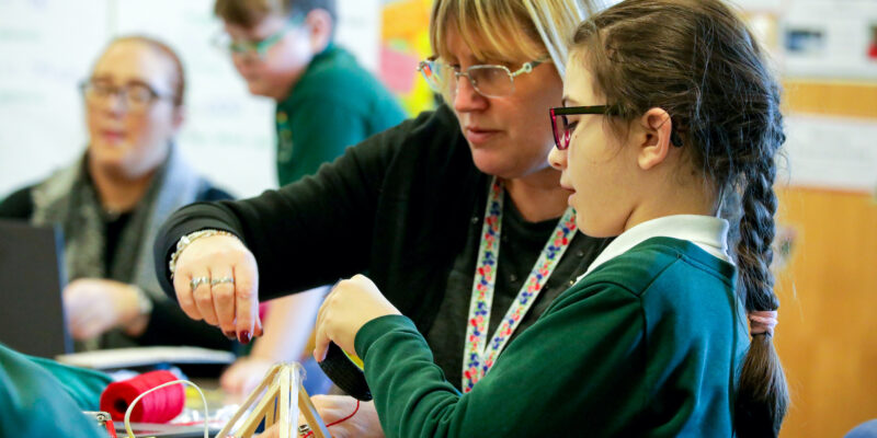 A computing teacher and a learner do physical computing in the primary school classroom.
