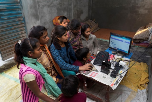 In rural India, a group of girls cluster around a computer.